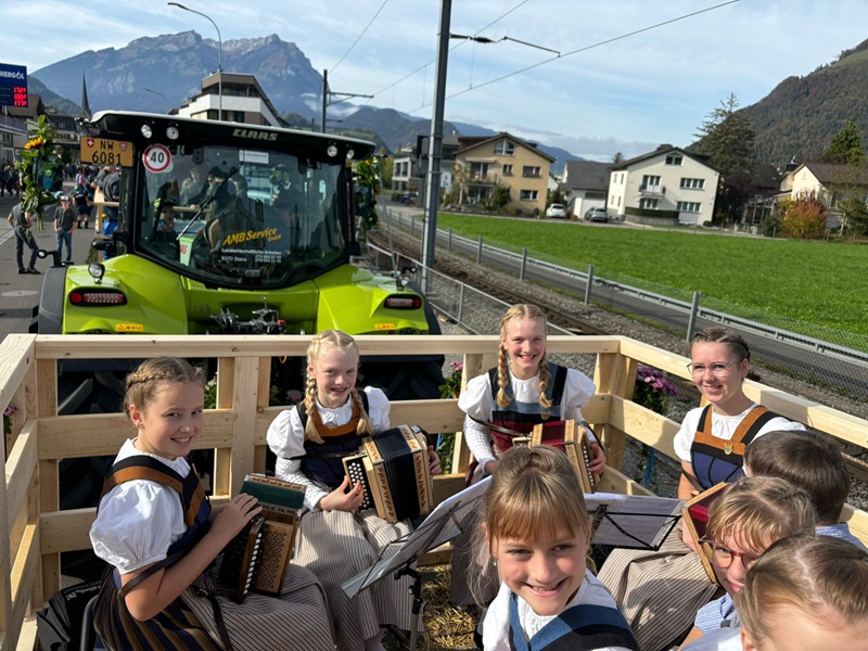 Kinderjodlercheerli im Wagen, vorne fährt 
				ein Traktor